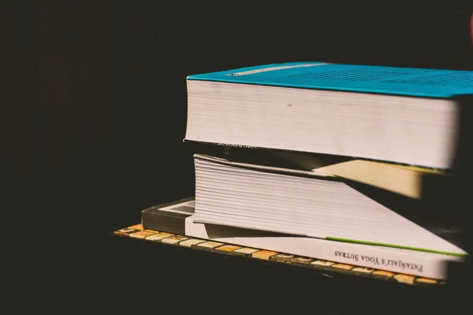 A small stack of books lit by warm light against a dark background