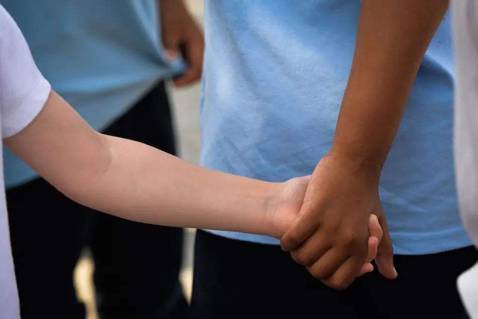 A child holding an adult's hand, seen from behind