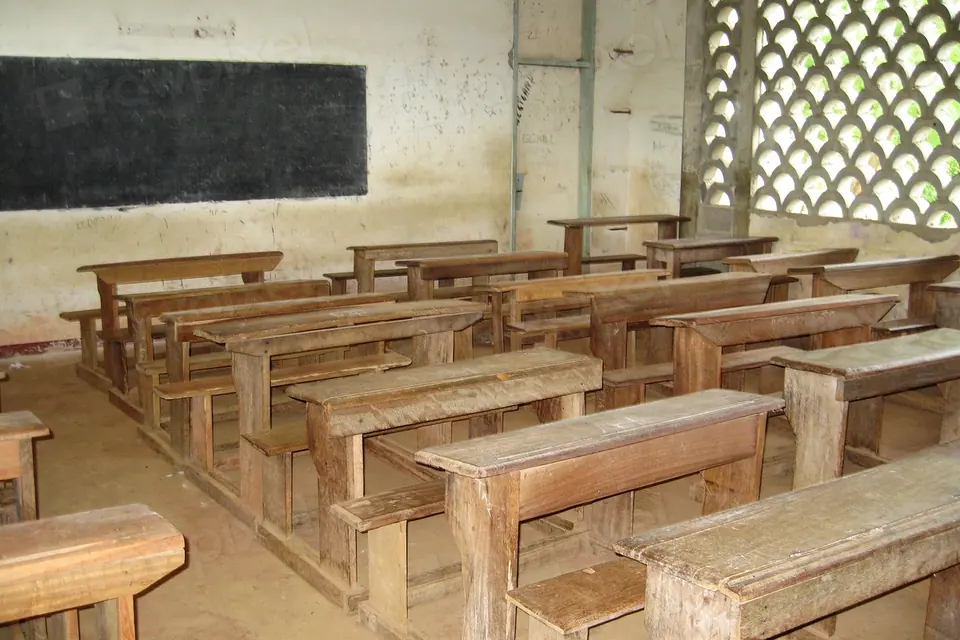 A simple classroom with rows of wooden benches and a blackboard