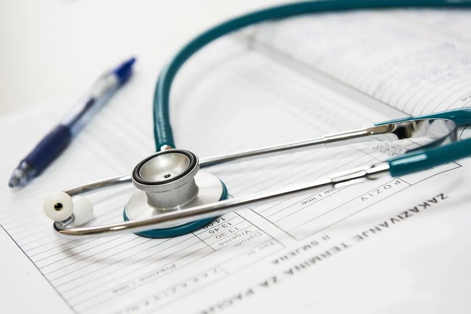 A stethoscope and a blue pen resting on a medical appointment form