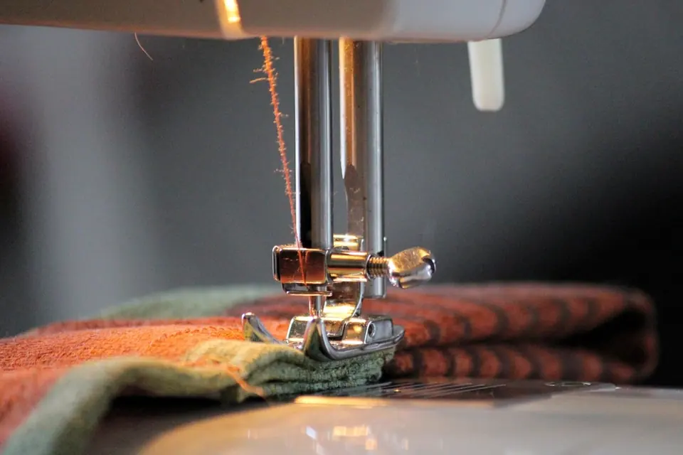 Close-up of a sewing machine stitching a folded piece of fabric
